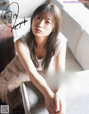 A woman in a white top and blue shorts posing for a picture.