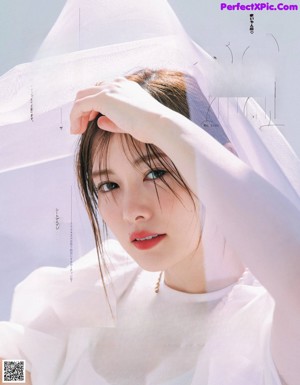 A woman in a white shirt and beige pants posing for a magazine.