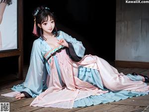 A woman in a blue and orange kimono sitting on a bed.