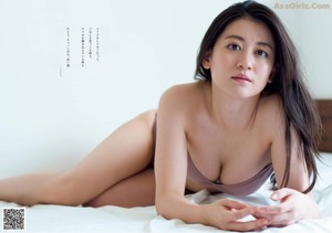 A woman laying on top of a bed next to a pillow.