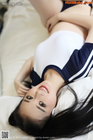 A woman in a blue and white bathing suit sitting on a bed.