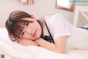 A woman laying on a bed with a pink pillow.