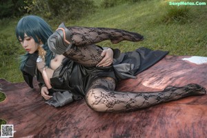 A woman with blue hair is sitting on a blanket.
