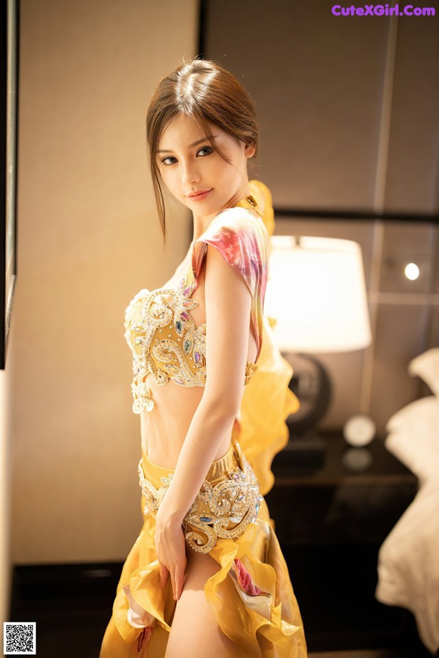 A woman in a yellow dress posing for a picture.