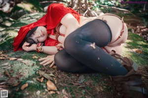 A woman dressed as a little red riding hood in the woods.