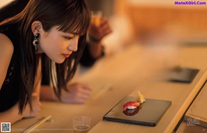 A woman sitting at a table with chopsticks and a glass of beer.