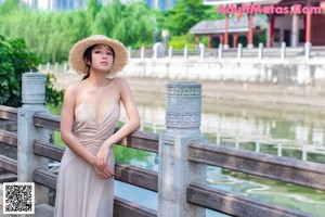 A woman in a blue dress and straw hat posing for a picture.