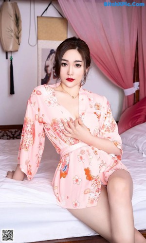 A woman laying on top of a bed in a pink dress.