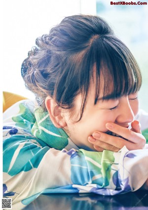 A woman in a blue and green kimono with a flower in her hair.