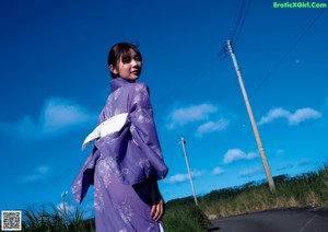 A woman in a purple kimono standing on some steps.