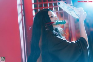 A woman in a black kimono holding a green flute.