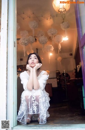 A woman in a white sweater is posing for a picture.