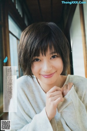 A woman in a black dress standing in front of a window.