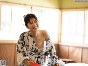 A woman sitting in front of a window covered in a blanket.