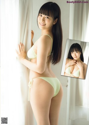 A woman in a white bikini posing in front of a brick wall.