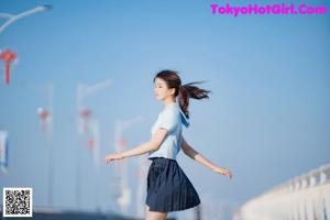 A woman in a blue shirt and skirt posing for a picture.
