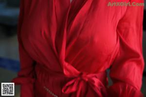 A woman in a red dress is laying on a bed.