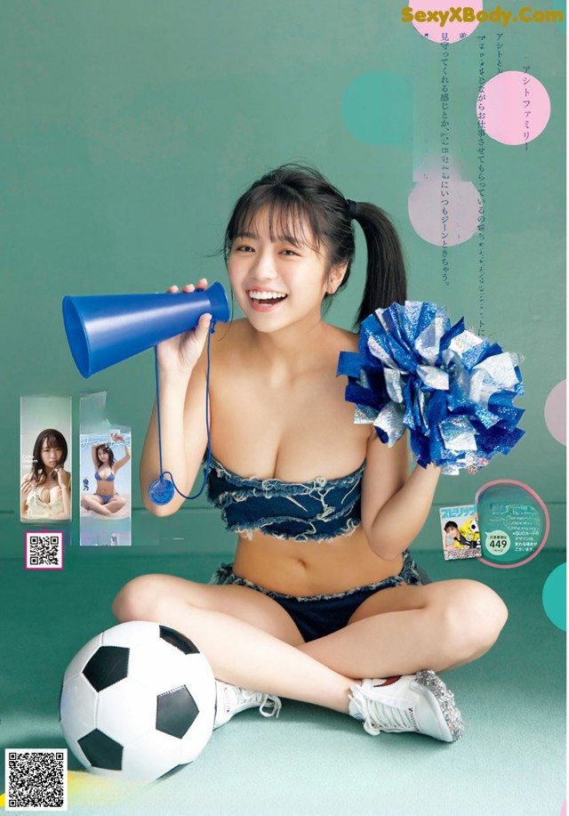 A woman in a cheerleading uniform holding a megaphone and a soccer ball.