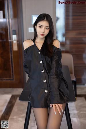 A woman sitting on a white couch with her legs crossed.