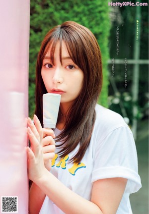 A woman in a white shirt is looking out of a window.
